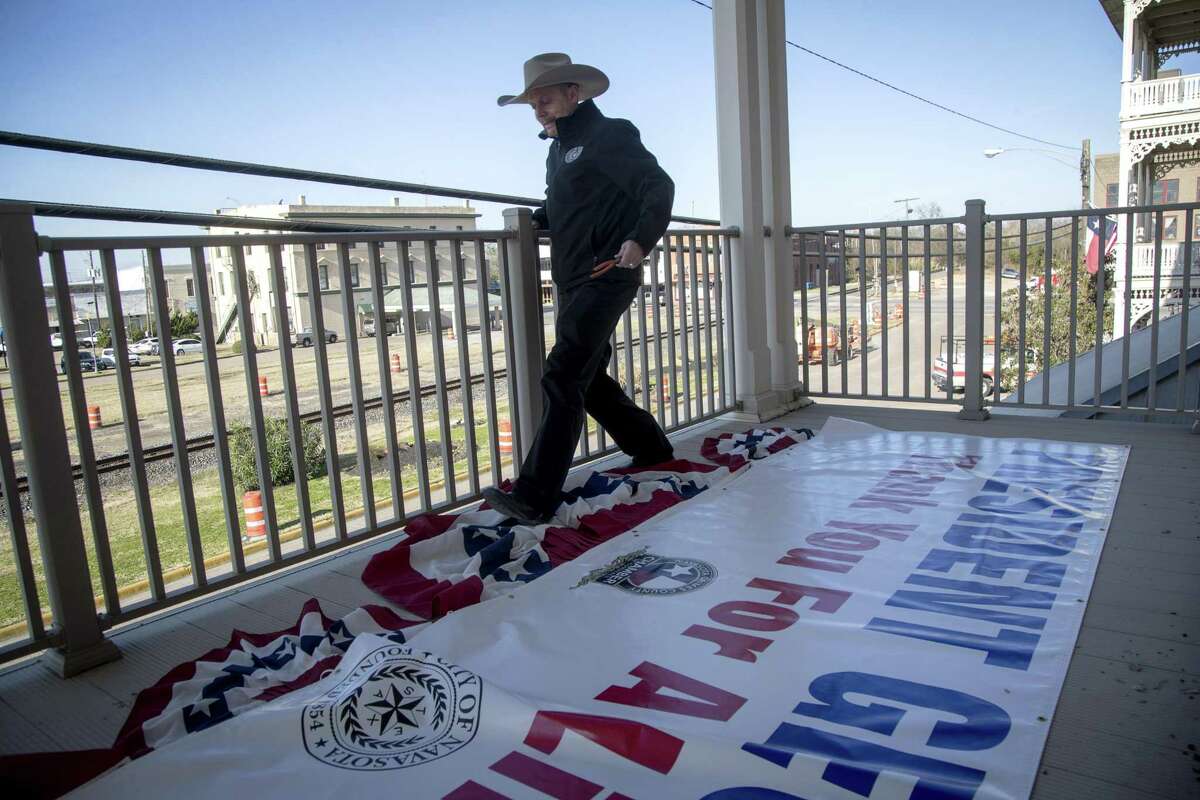 Brad Stafford, the Navasota city manager, prepares a sign that will be hung from a building overlooking the route of former President George H. W. Bush's funeral train, Wednesday, Dec. 5, 2018, in Navasota.
