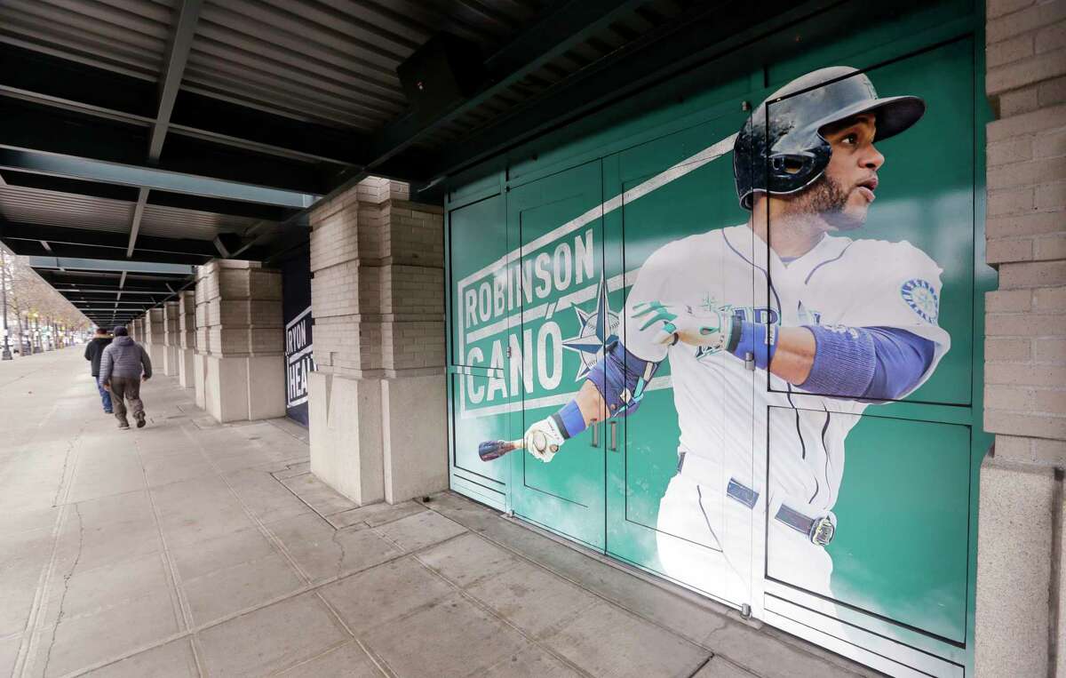 In this photo taken Thursday, Nov. 29, 2018, an oversized photo of Seattle Mariners' Robinson Cano stands along a sidewalk at the team's ballpark in Seattle. In a deal announced Monday, Dec. 3, 2018, the New York Mets have acquired longtime star second baseman Cano and major league saves leader Edwin Diaz from the Seattle Mariners in a seven-player trade. (AP Photo/Elaine Thompson)
