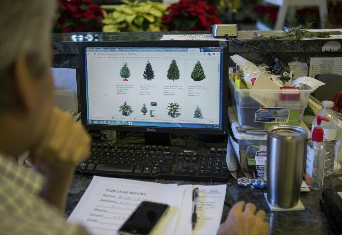 National Tree & Shrub owner Richard Devine takes a look at the Christmas trees available on Amazon while sitting at the front desk of his nursery that sells Christmas trees, Monday, Dec. 3, 2018 in Houston. The nursery on Yale Street procures their Christmas trees from Oregon and offers several services including flocking and home delivery.