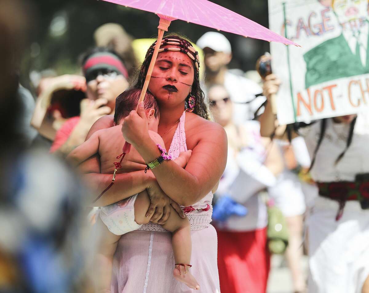 Diana Yolotl of Houston holds onto her 9-month-ould daughter Ikal Citlali as she prepares to march after an immigration rally on Saturday, June 30, 2018 in Houston. Rallies were held across the nation calling on federal agencies to reunite families separated at the border under Trump's "zero tolerance" policy, as well as calling for the abolishment of ICE.