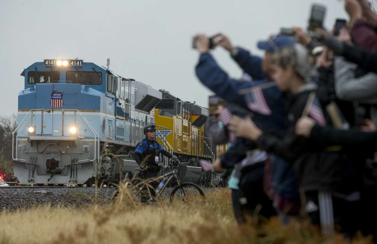 People record and watch the arrival of the train carrying former President George H.W. Bush's body Thursday, Dec. 6, 2018, in College Station, Texas.