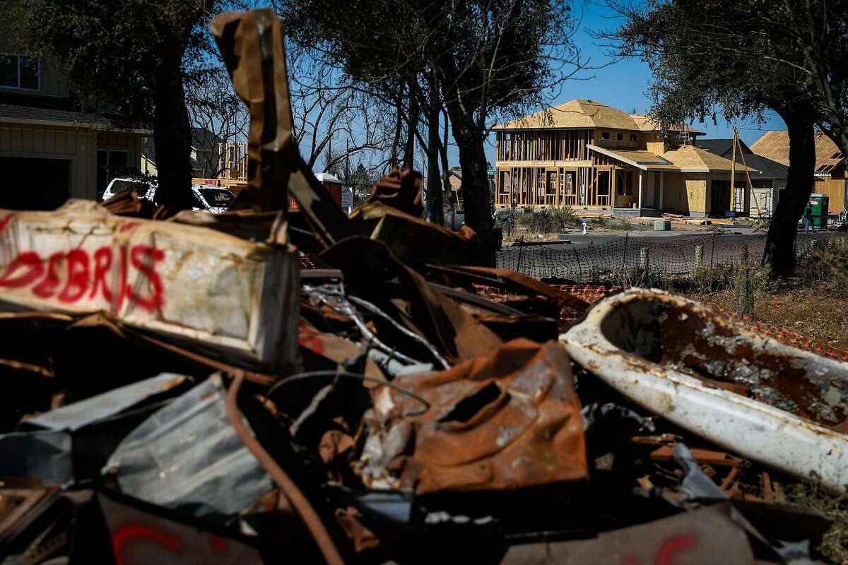 A house is seen under construction while debris from the Tubbs fire is seen (left) in the Coffey Park neighborhood nearly one year after the Tubbs fire ravaged the area in Santa Rosa, California, on Thursday, Sept. 20, 2018.