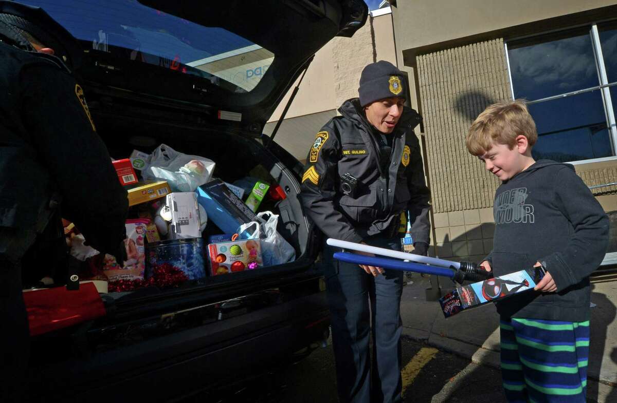 Norwalk police seargent Sofia Gulino receives a donation from Norwalk resident P.J. Small, 6, during the Norwalk Police Department third annual Stuff-A-Cruiser" toy drive event Friday, December 7, 2018, at the Walmart on Main Ave. in Norwalk, Conn. Officers accepted donations of new, unwrapped toys for children ages infant-15 years old which benefit local families in need through the Domestic Violence Crisis Center, the Human Services Council, The Open Door Shelter and the Norwalk Housing Authority.
