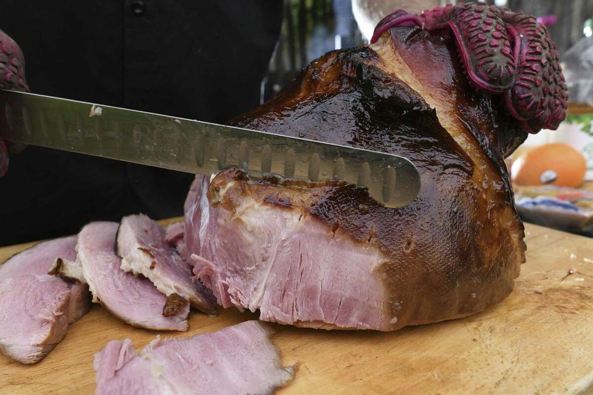 Chuck Blount slices a ham shank glazed with brown sugar, Dijon mustard, honey, fresh orange juice and apple juice. It was smoked for four hours, until internal temperature hits about 145 degrees.