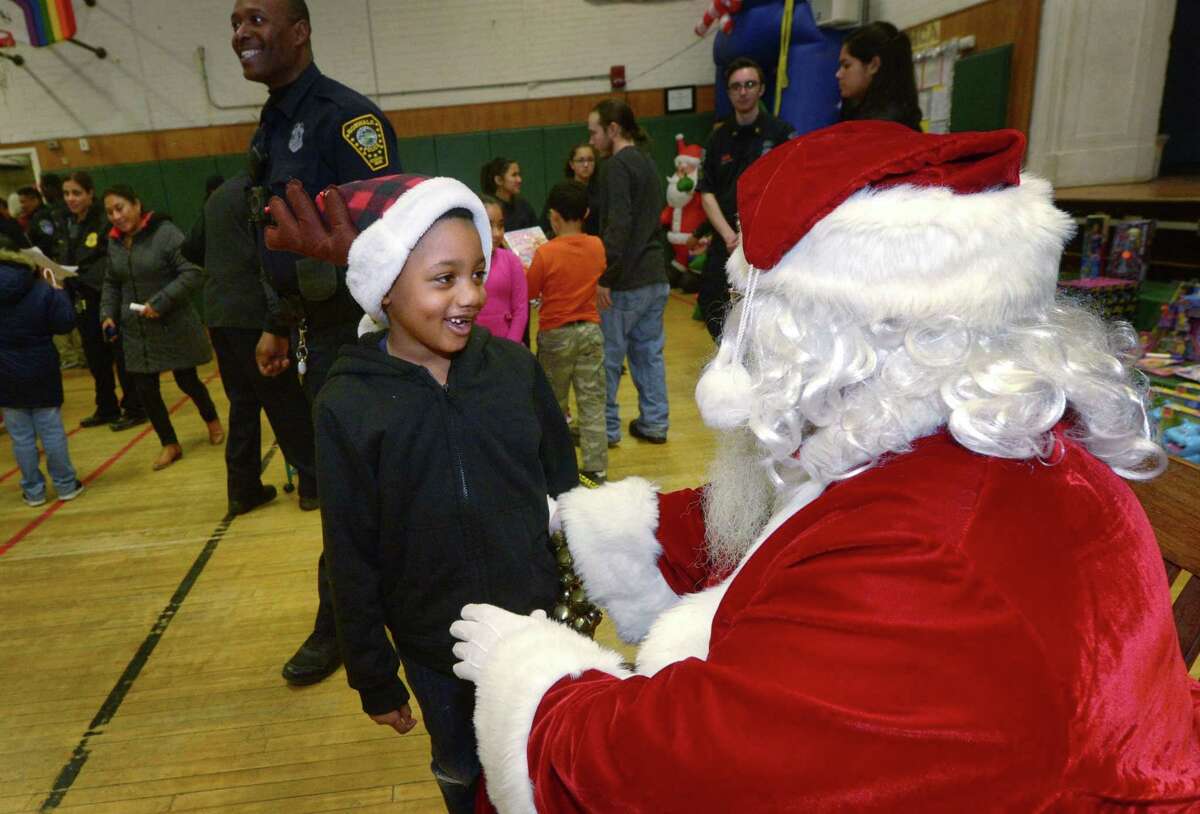 Tyler Geneus, 6, greets Santa Claus, aka retired police officer Joe Kubik, Saturday, December 8, 2018, during The Norwalk Community Police Childrens Holiday Party Saturday at Columbus Magnet School in Norwalk, Conn. The event provided gifts for over 100 needy children.