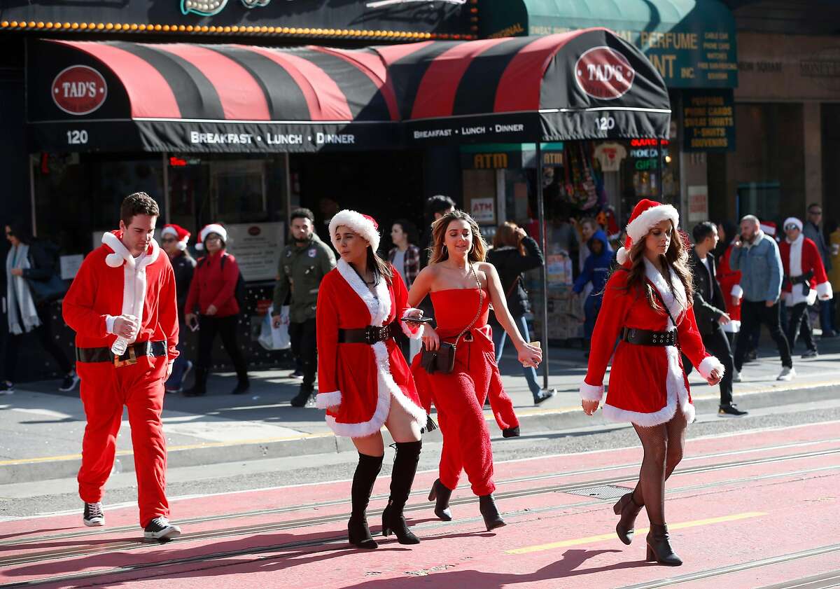 Revelers dressed as Santa Claus cross Powell Street near Union Square for the annual SantaCon in San Francisco, Calif. on Saturday, Dec. 8, 2018. The event was held despite the denial of a permit issued by the city.