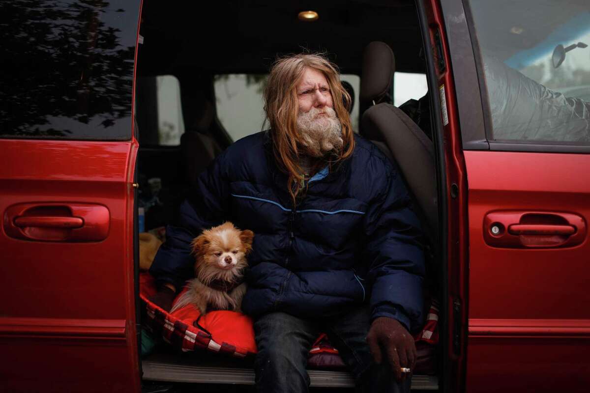 Camp Fire evacuee Ron Irick sits in his friends car with his recently rescued dog, Jojo, while at a makeshift evacuation site at Walmart in Chico on Thursday, November 15, 2018.