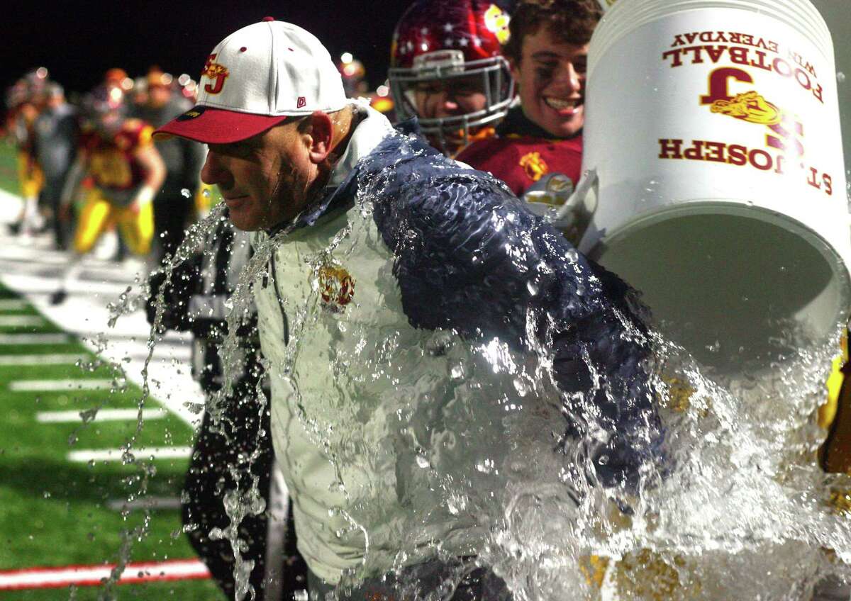 St. Joseph players give head coach Joe DellaVecchia a celebratory water-cooler shower after beating Berlin in Class M state championship on Saturday in Shelton.