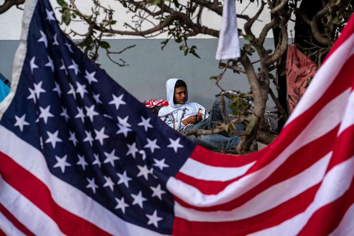 A Central American migrant who has trekked for a month across Central America and Mexico in the hopes of reaching the United States with a caravan, remain next to a US national flag at a temporary shelter in Tijuana, Baja California State, Mexico, near the border with the US, on November 28, 2018. (Photo by Guillermo Arias / AFP)GUILLERMO ARIAS/AFP/Getty Images