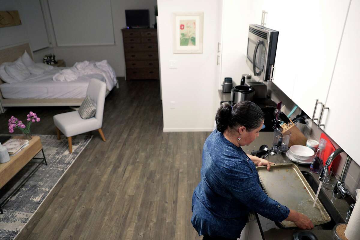 Lourdes Dobarganes scrubs a sheet pan as she cleans the studio apartment of one of her clients in San Francisco, Calif., on Monday, December 10, 2018. Dobarganes is looking into using Alia, a new service for people who clean houses to have their employers chip in to provide some benefits for them, such as paid time off or life insurance.