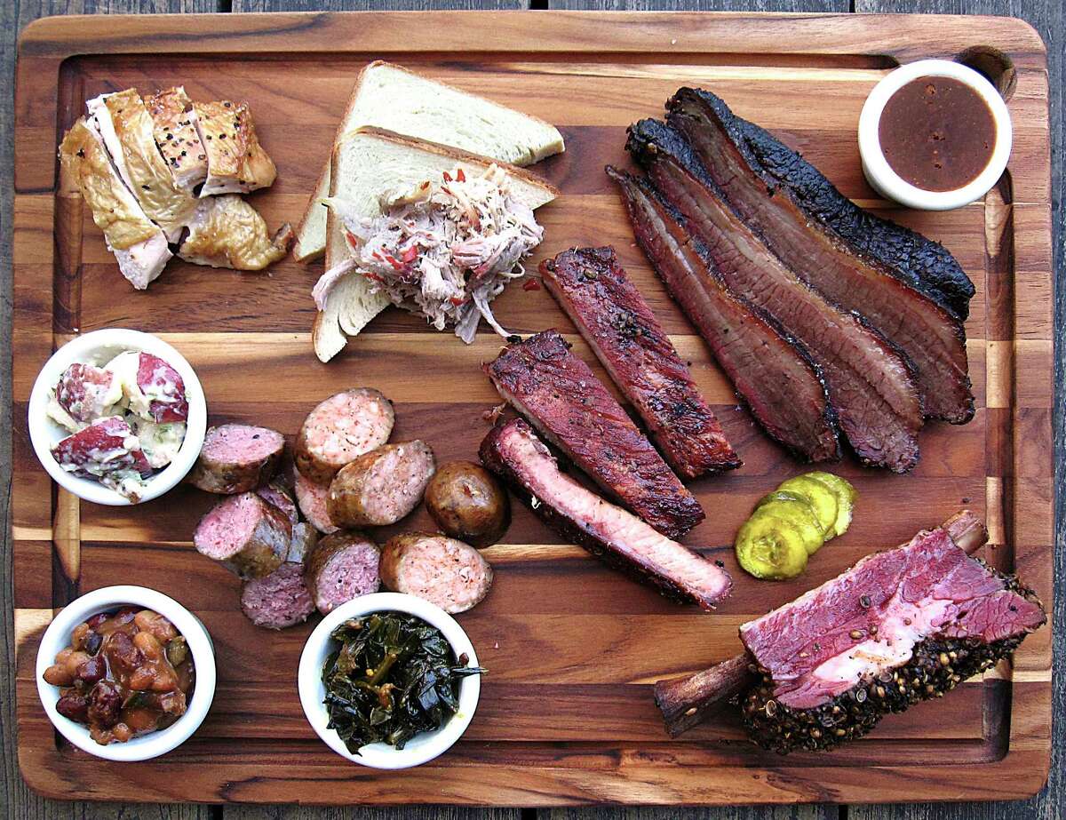 Meat and sides from The Granary 'Cue & Brew at the Pearl in San Antonio. Clockwise from top left: chicken, buttermilk bread, pulled pork, brisket, barbecue sauce, pastrami beef rib, housemade pickles, pork ribs, smoked collard greens, pork sausage, beef sausage, burnt end baked beans and German potato salad.