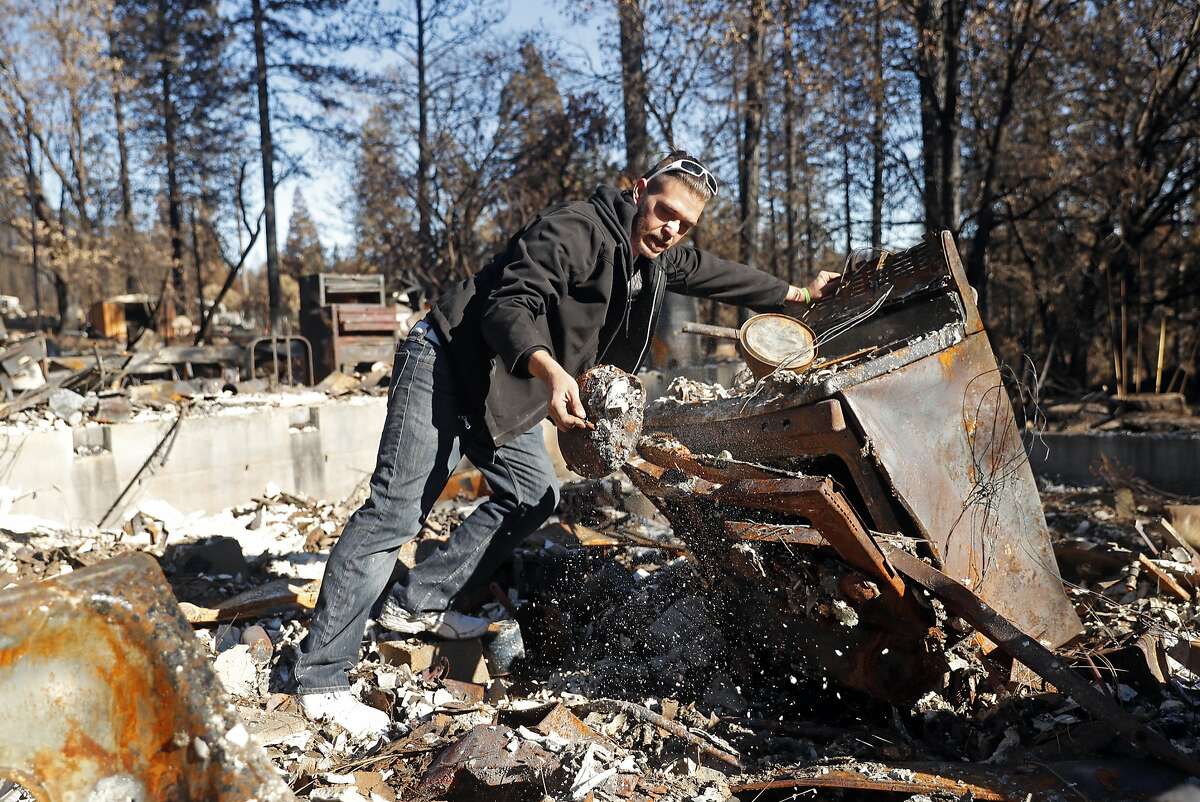In the aftermath of the Camp Fire, Jake Belculfino, salvages items from her mother's kitchen, as his family looks through the remains of their house along Pentz Road in Paradise, Calif. on Thursday, December 6, 2018.