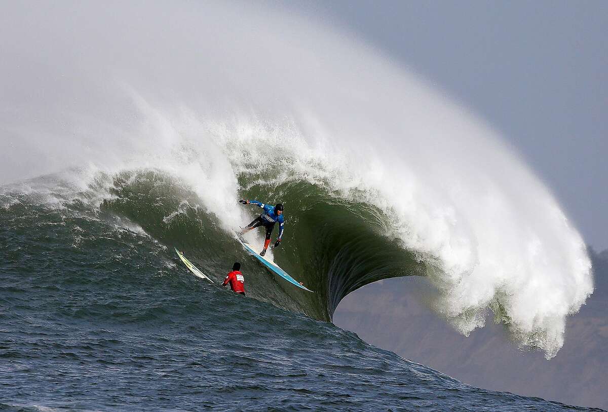 Peter Mel catches a wave as Colin Dwyer, below, is near during the second heat of the first round of the Mavericks Invitational big wave surf contest Friday, Jan. 24, 2014, in Half Moon Bay, Calif. Mel is the defending champion of the event. (AP Photo/Eric Risberg)