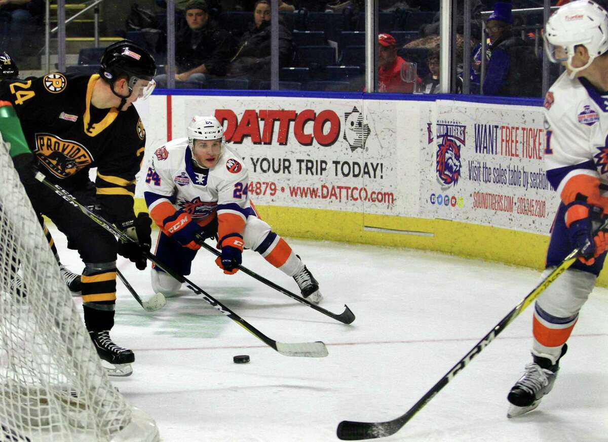 The Sound Tigers’ Travis St. Denis (24) passes the puck over to teammate Ben Holmstrom, right, as Providence’s Cameron Hughes (24) tries to disrupt on Dec. 2 at the Webster Bank Arena in Bridgeport.