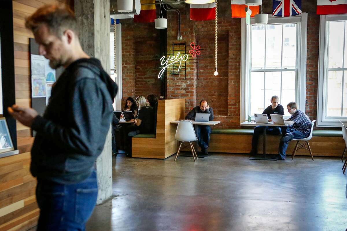 Yelp employees work at its San Francisco headquarters in 2018. The company is also shrinking its offices in other cities.