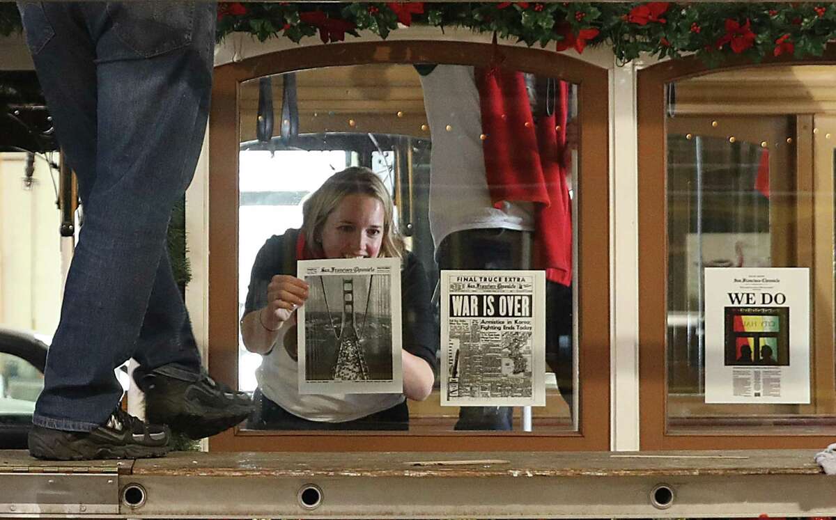 Heather Knight decorates a cable car with copies of historic Chronicle front pages.