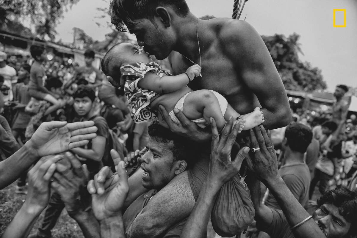 Winners of the 2018 National Geographic Photo Contest, Third Place, People  A Hindu devotee kisses his newborn baby during the Charak Puja festival in West Bengal, India. Traditional practice calls for the devotee to be pierced with a hook and sometimes swung from a rope. This painful sacrifice is enacted to save their children from anxiety. While covering the festival, I was able to view the religious practice from the perspective of Hindu devotees. I tried to capture the moment of love and bonding between a father and his child—and show a father's concern for his little son. Link: https://yourshot.nationalgeographic.com/photos/12184811