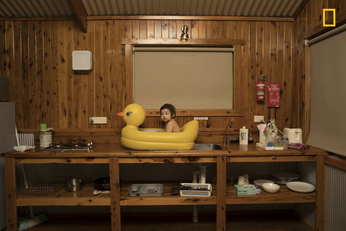 Winners of the 2018 National Geographic Photo Contest, 2nd Place, People On a family holiday driving from Sydney to Uluru, we stopped at a roadside motel in the small rural township of Nyngan, on the edge of Australia's outback. The area is in the wheat belt, and it was unusually hot for that time of year—over a hundred degrees Fahrenheit and very dusty. Our daughter, Genie, is seen here enjoying a refreshing bath in a rubber ducky perched on the sink. Link: https://yourshot.nationalgeographic.com/photos/12919552