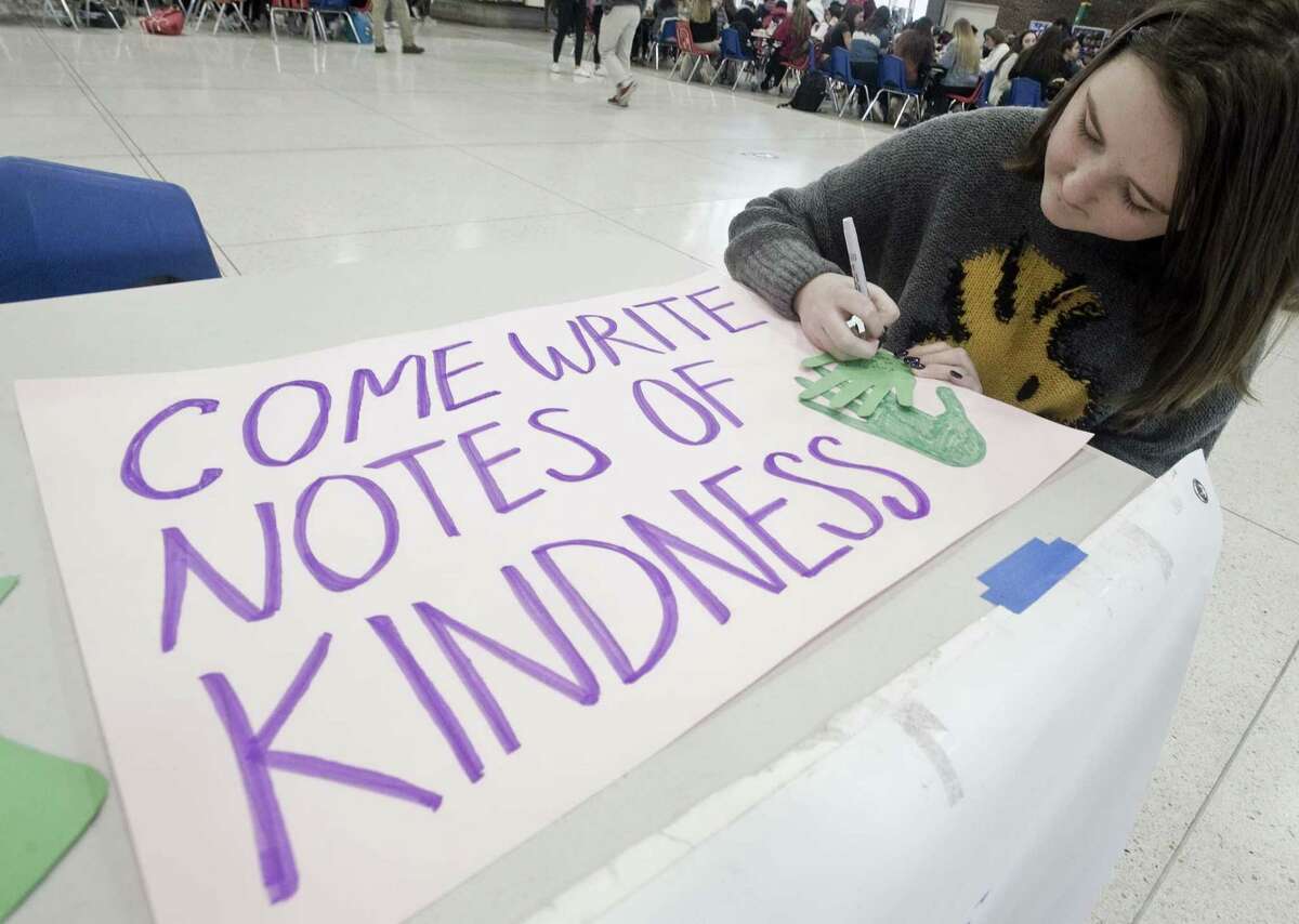 Kaja Tully, a freshman, writes a note at the Roots and Shoots table in the student center at Greenwich High School, for the anniversary of the Sandy Hook shooting. Friday.