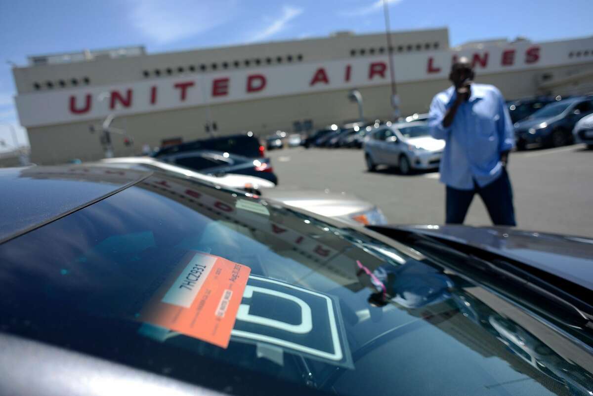 An Uber driver smokes a cigarette as he waits in a parking lot near SFO Airport in San Francisco, California, on Wednesday, June 17, 2015.