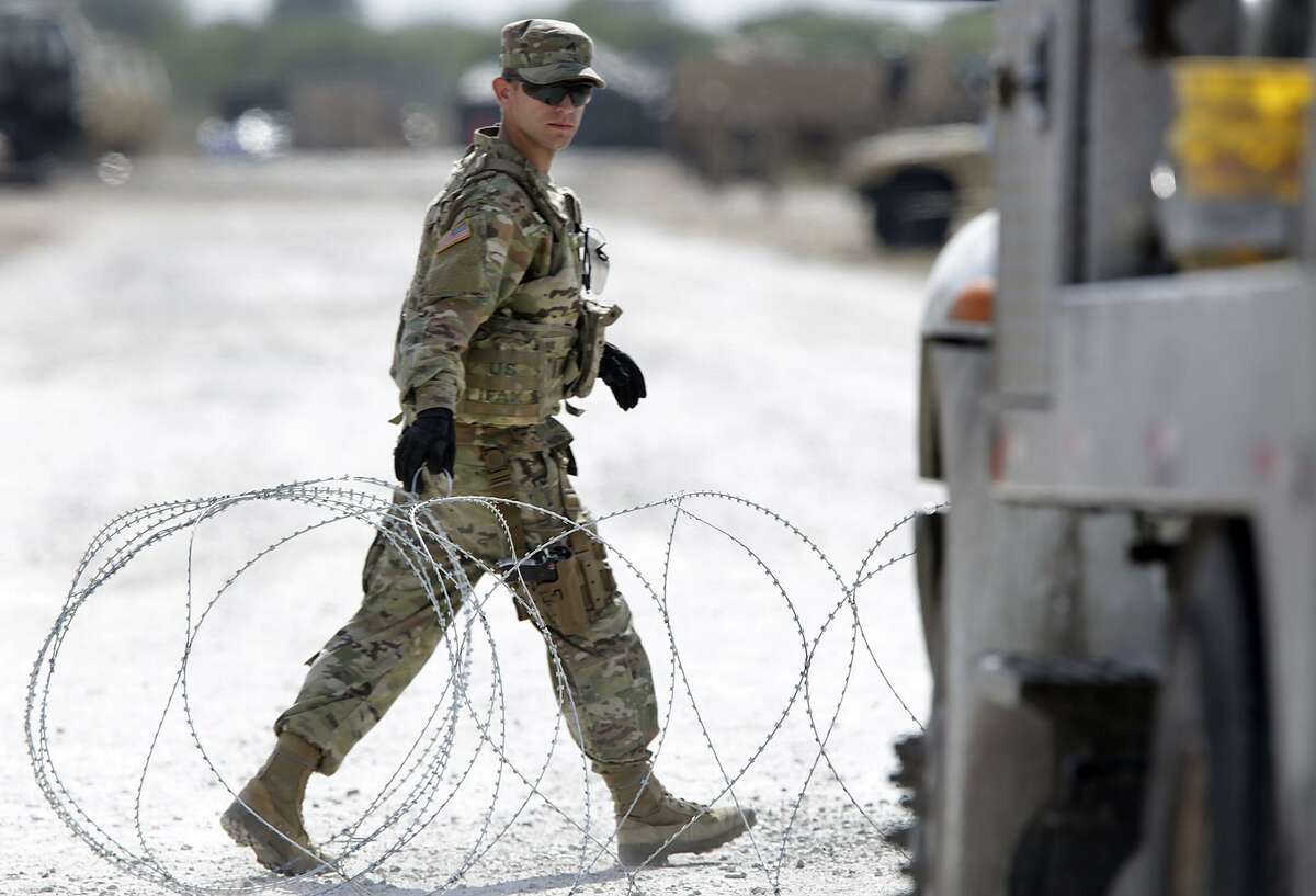 A member of the Military Police opens a razon wire gate for a military vehicle to enter a camp next to the Donna-Rio Bravo International Bridge, on Tuesday, Dec. 4, 2018.