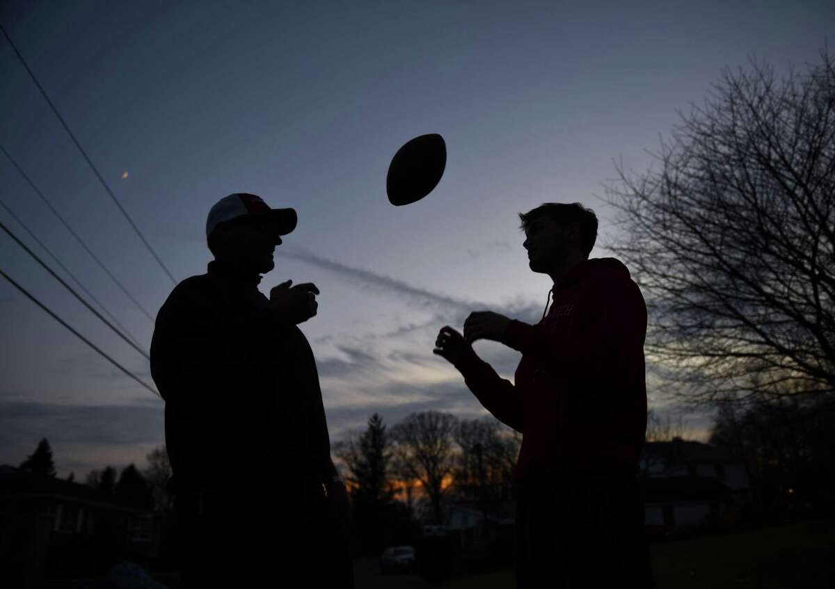 Larry DeLuca, left, tosses a football to his son, L.J. DeLuca, at their home in the Cos Cob section of Greenwich, Conn. Wednesday, Dec. 12, 2018. L.J. played linebacker on Greenwich High School's 2018 undefeated team and his father Larry played defensive end on the 1983 undefeated team. Despite an undefeated record, Larry's 1983 squad finished ranked No. 3 in the state, while L.J.'s team was ranked first, and Larry admits that he thinks his son's team is better.