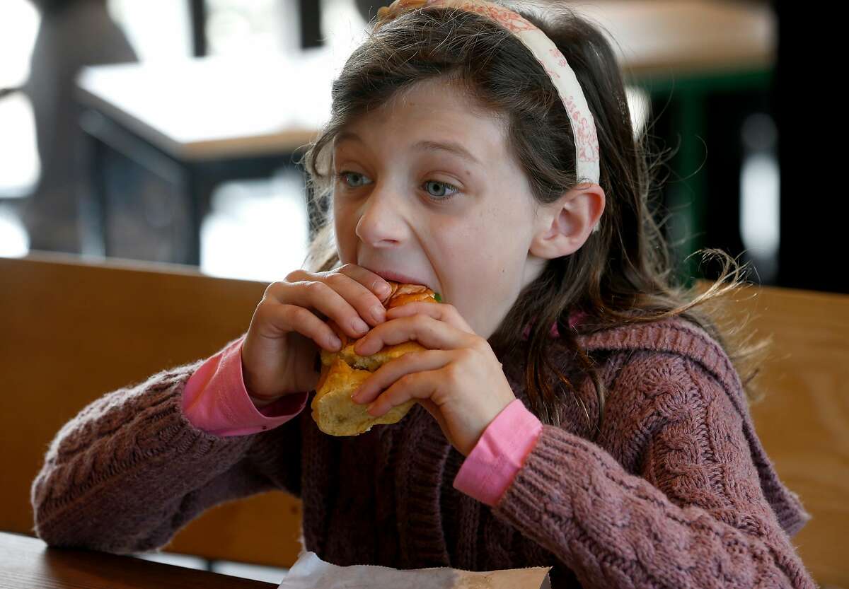 Elsa Wick, 7, bites into a Shack Burger after the first Shake Shack restaurant in Northern California opens at the Stanford Shopping Center in Palo Alto, Calif. on Saturday, Dec. 15, 2018.