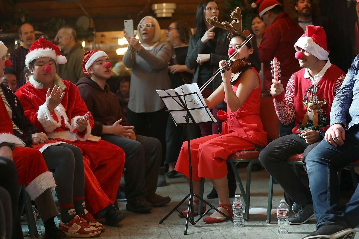 Para educator Sunghye Lee (middle, right) plays the violin next to Josue Colindres (right) at the singalong concert at Arc on Monday, Dec. 17, 2018, in San Francisco, Calif. Special education high school and above SFUSD students present holiday singalong concert at Arc.