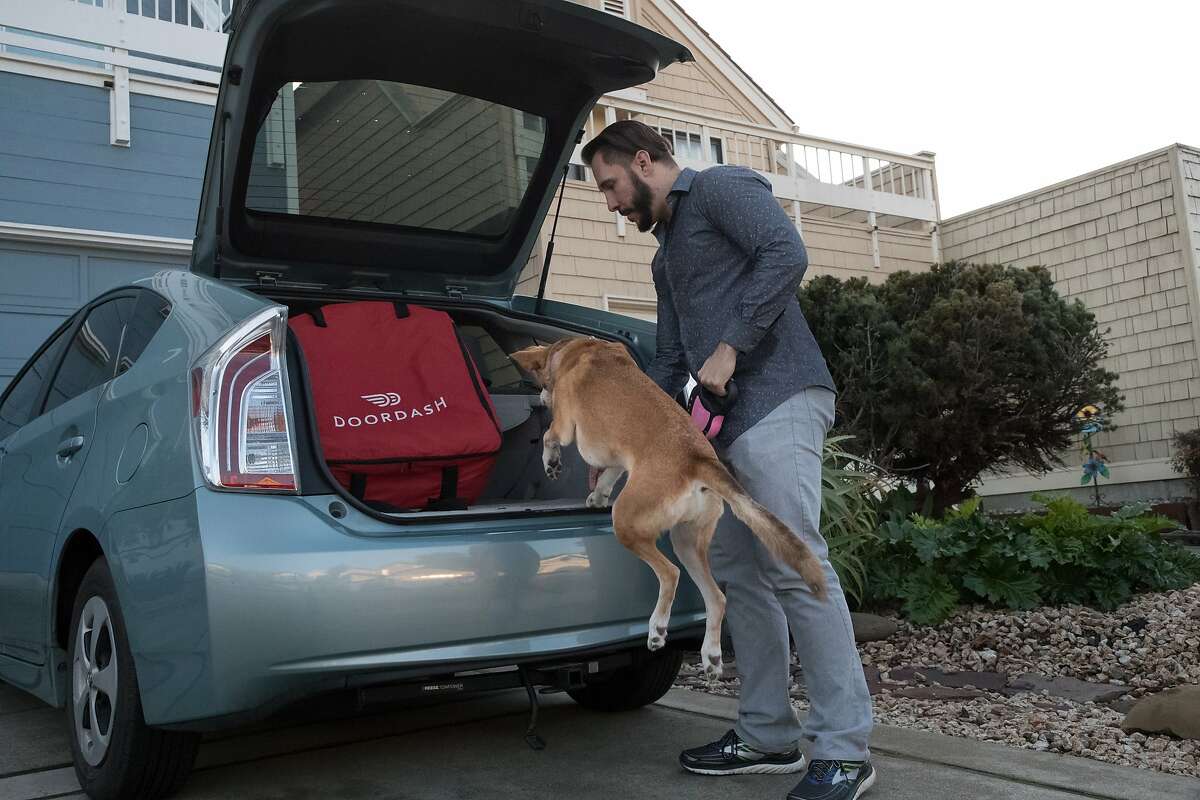 Jon Gallez lets his dog Mia hop into the car and she sits in the passenger seat during Doordash deliverys on Saturday, Dec. 8, 2018, in San Mateo, Calif.