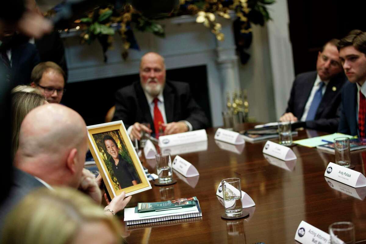 Scarlett Lewis holds up a photo of her son Jesse Lewis, who was killed in the Sandy Hook school shooting, during a meeting with President Donald Trump on the Federal Commission on School Safety report, in the Roosevelt Room of the White House, Tuesday, Dec. 18, 2018, in Washington.
