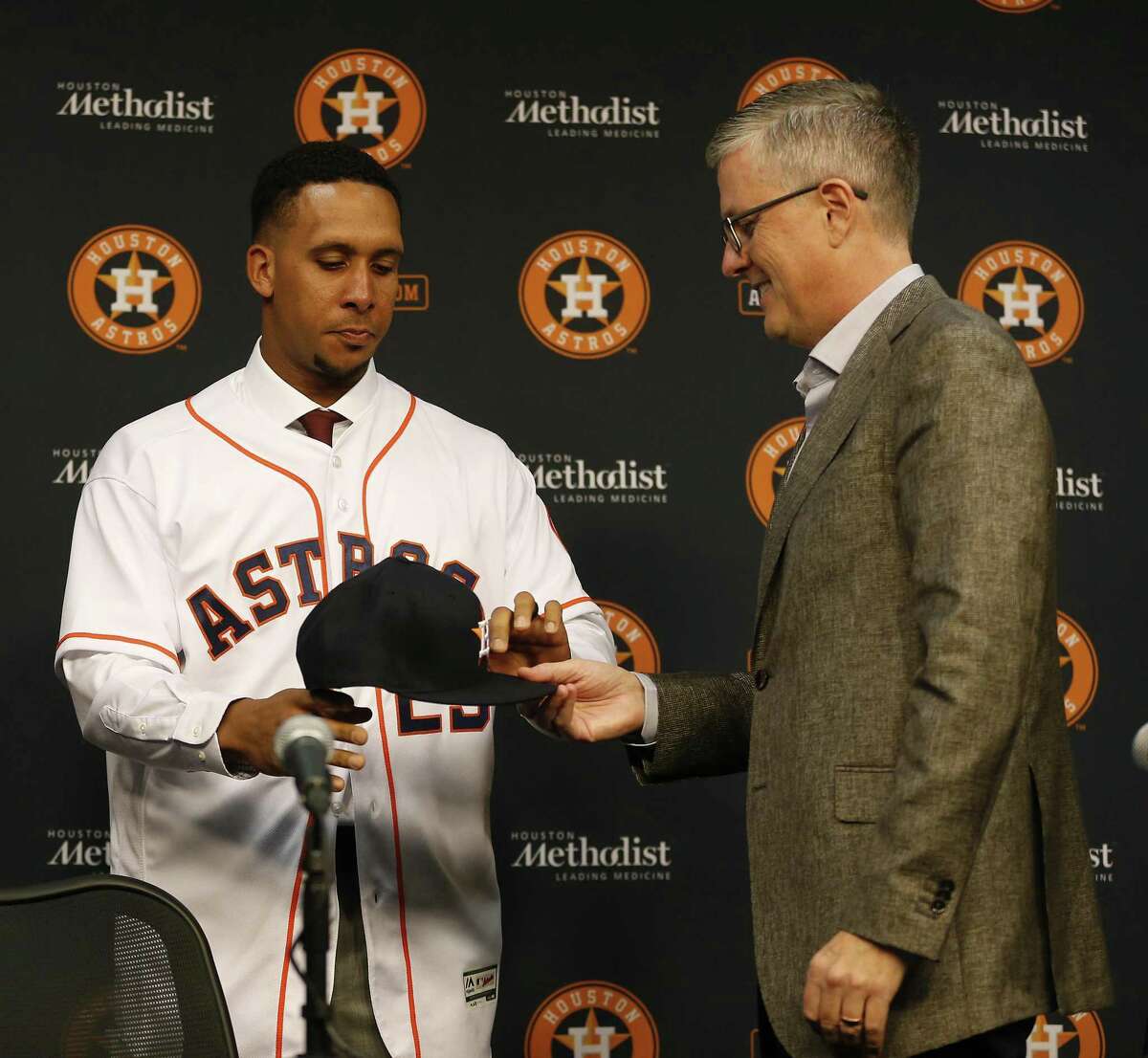 Michael Brantley puts on his Astros jersey as Astros President of Baseball Operations and General Manager Jeff Luhnow holds his baseball cap as the organization announced the signing of Brantley at Minute Maid Park, Wednesday, Dec. 19, 2018, in Houston. Brantley signed a two-year contract with the outfielder.