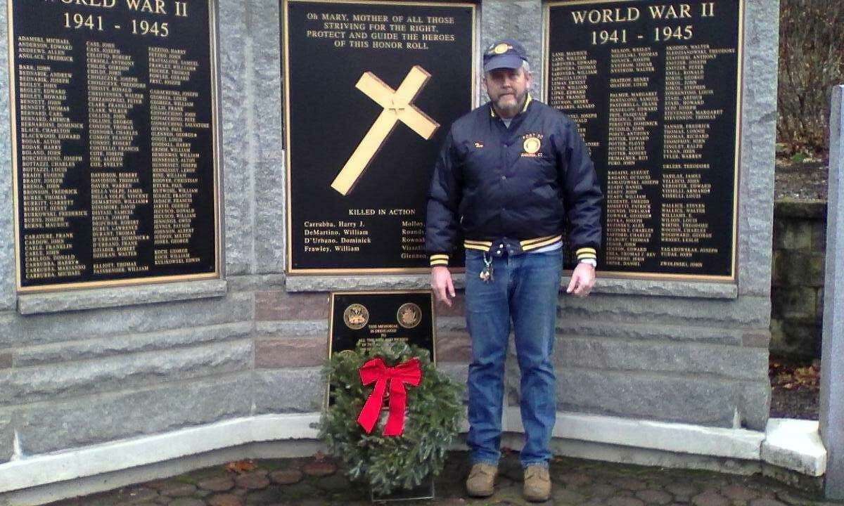 Tom Henri with a wreath placed by the Ansonia American Legion Post 50 at the Woodbridge Avenue Veterans Memorial.
