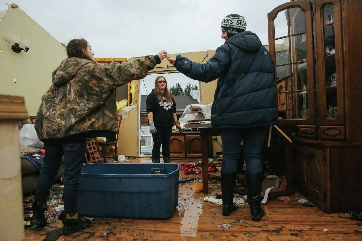 Jasmin Mueller, 16, left, is handed a key by her aunt Melinda St. John, right, as Mueller's sister Hannah, 20, helps to clean up after a tornado tore the roof off of their house Tuesday in Port Orchard, Wednesday, Dec. 19, 2018.