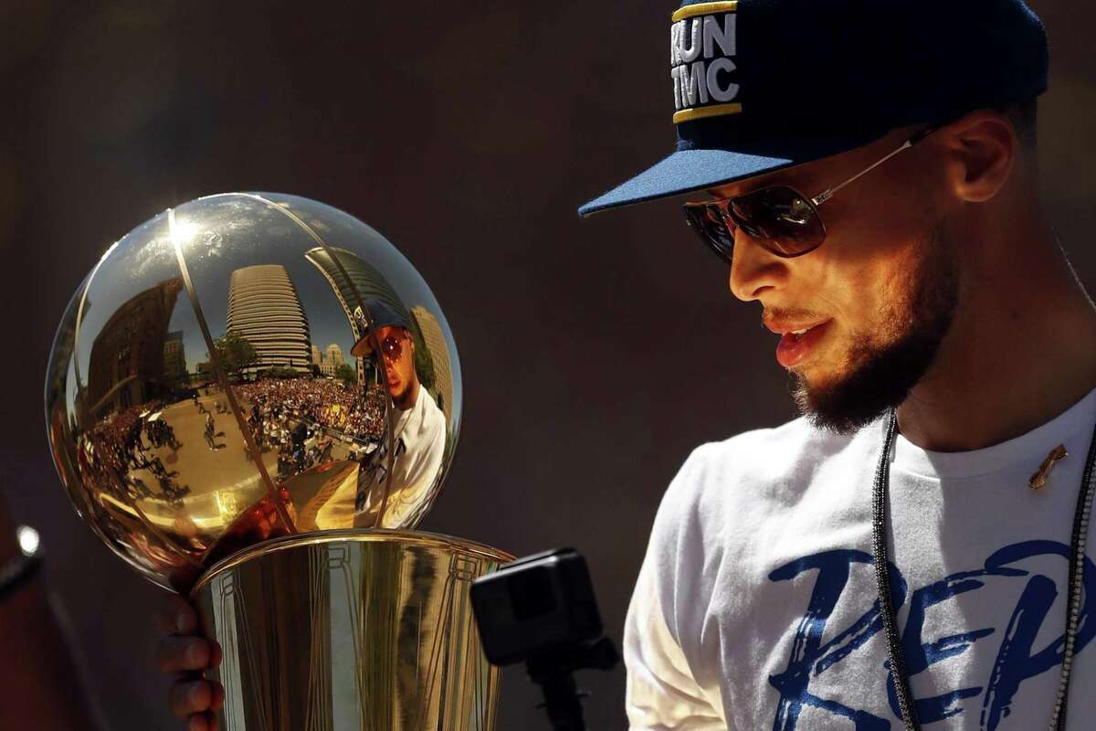 Warriors guard Stephen Curry holds the Larry O’Brien NBA championship trophy during the team’s victory parade in Oakland on June 12.