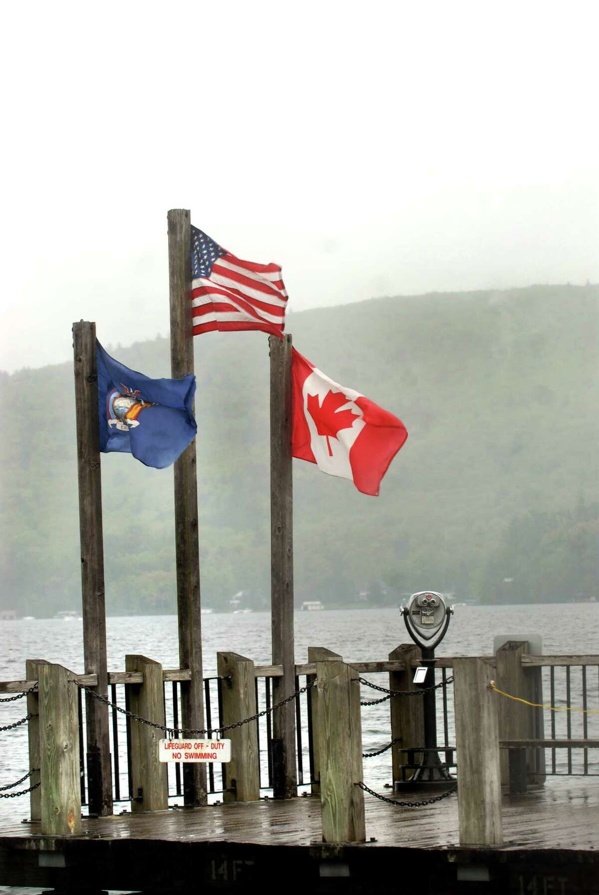 Despite sagging Canadian opinions about the United States and President Donald Trump, business and tourism ties between New York and Canada appeared not to have suffered this summer, according to officials. Here, the Canadian flag flies with the U.S. flag and the New York State flag on the public dock at the tourist destination of Lake George. (Times Union archive)
