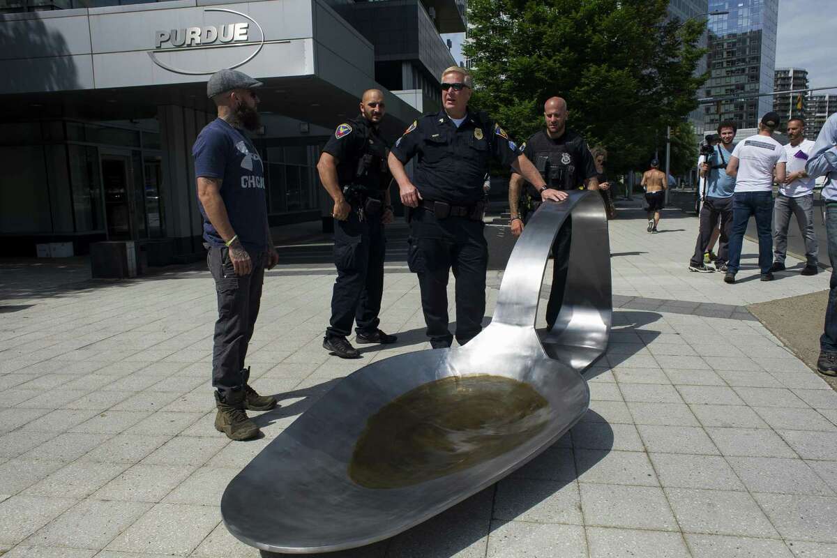In a file photo from June, Stamford police are shown with a 13-foot-long sculpture of a spoon that was placed outside the headquarters of Purdue Pharma, the makers of the painkiller OxyContin, as part of a protest against the opioid crisis. The sculpture, weighing 700 pounds, depicted the type of spoon addicts use to melt heroin before injecting it.
