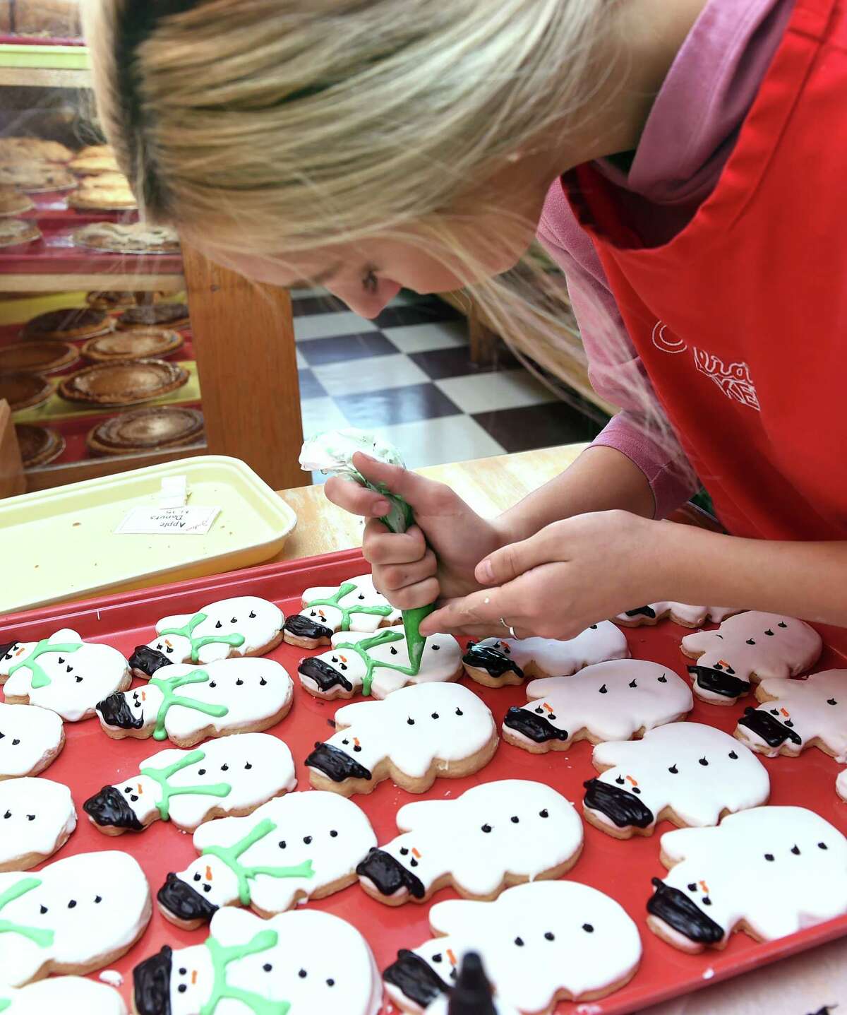 Briana Eagley decorates snowmen sugar cookies with icing at Julia's Bakery in Orange on December 20, 2018. The store sells around 100 dozen of the decorated sugar cookies during the holiday season.