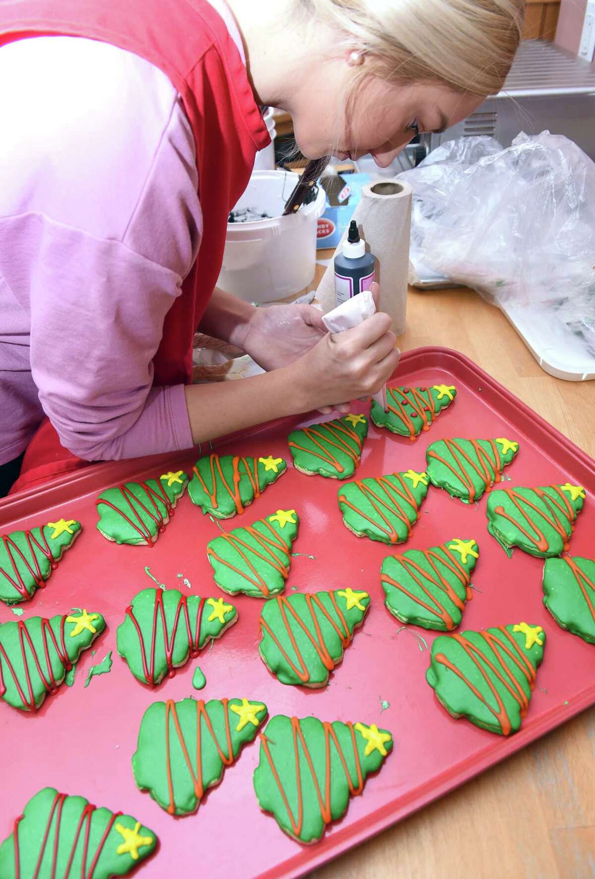 Briana Eagley decorates Christmas tree sugar cookies with icing at Julia's Bakery in Orange on December 20, 2018. The store sells around 100 dozen of the decorated sugar cookies during the holiday season.