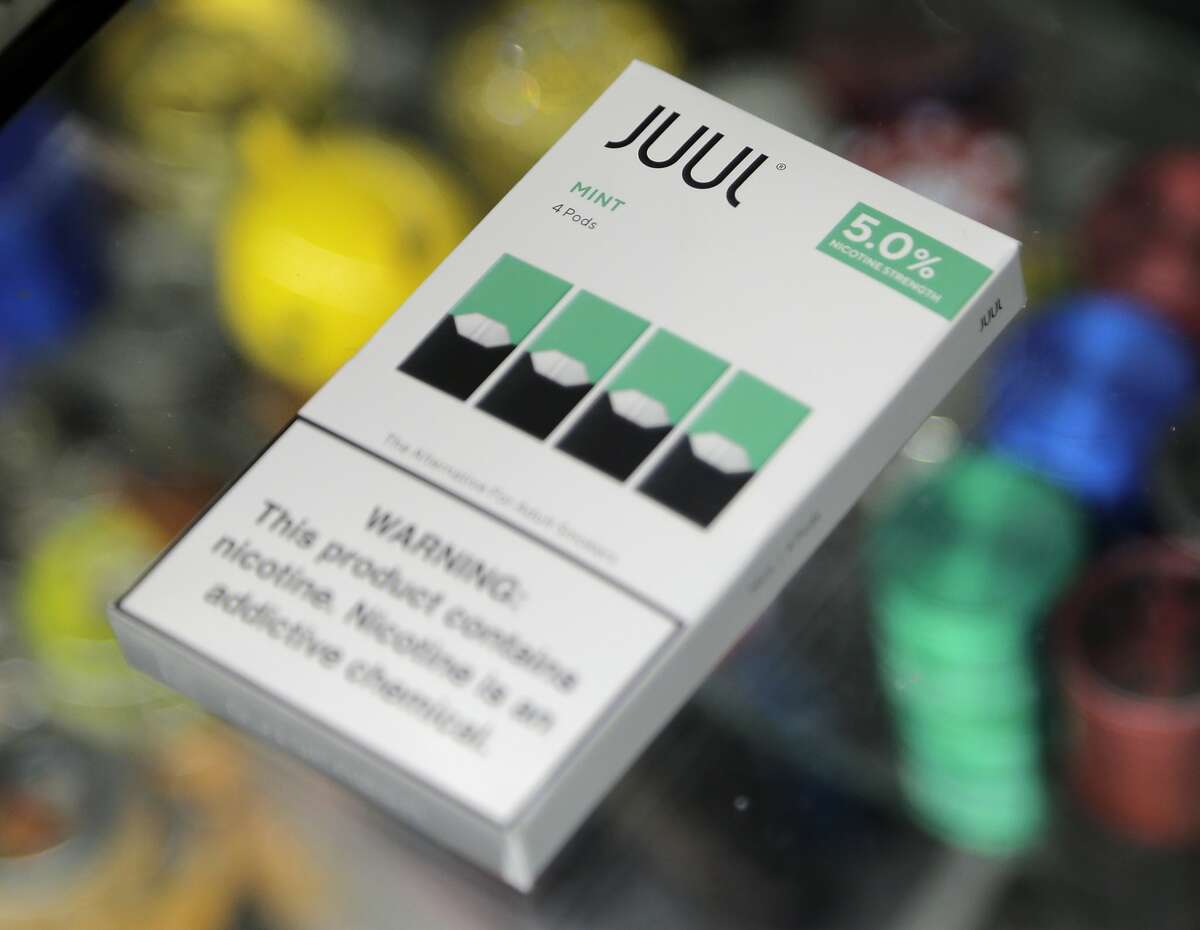 A woman buys refills for her Juul at a smoke shop in New York, Thursday, Dec. 20, 2018. 