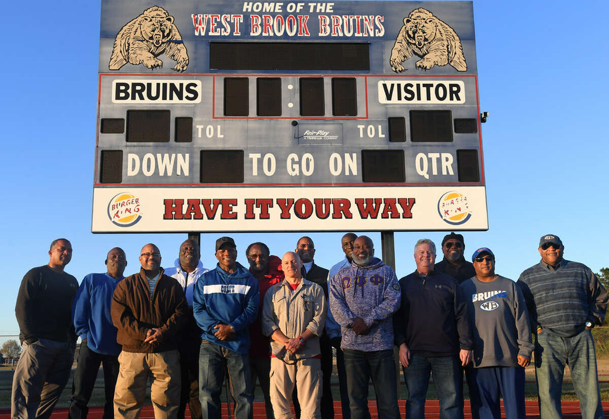 Fourteen members of the 1982 West Brook football team pose for a photo on the track at Alex Durley Stadium on Thursday. The inaugural season for the Bruins, the team was the first to play in a state tourney and the last since the 2018 team who plays for the title today. Photo taken Thursday, 12/20/18