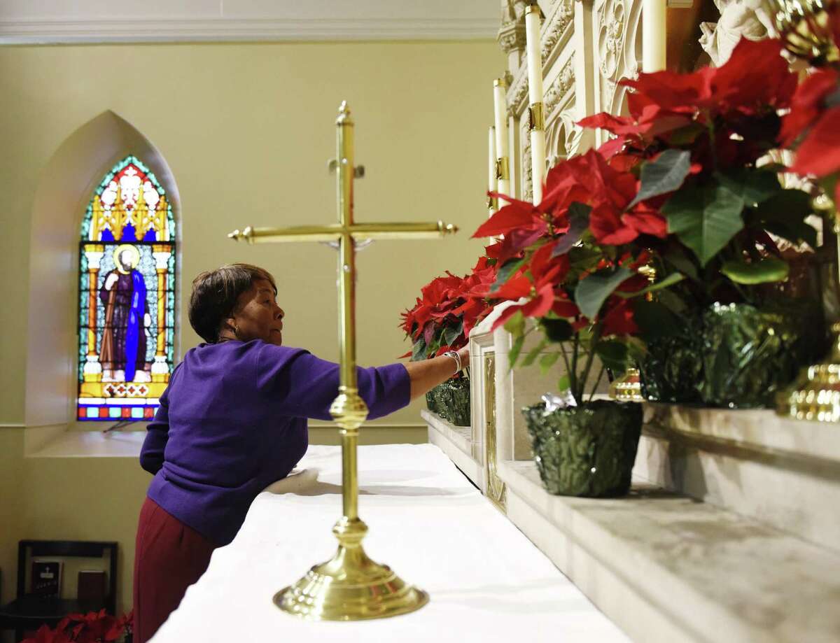 Altar Guild member Syline Aarons-Bent sets up Poinsettias in preparation for the Christmas Day service at St. Andrew's Episcopal Church in Stamford, Conn. Sunday, Dec. 23, 2018.