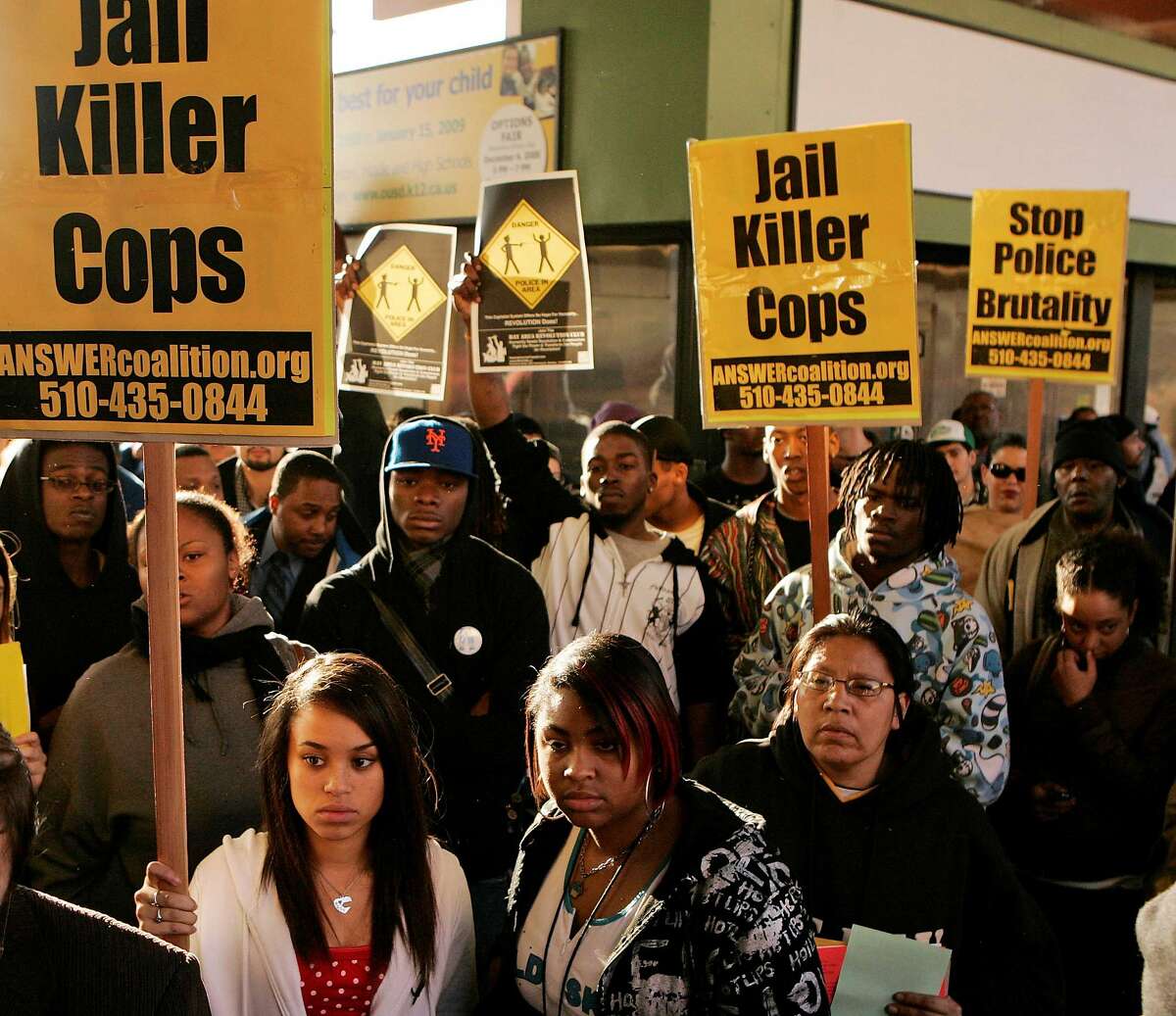 Demonstrators hold sings during a protest of the shooting death of Oscar Grant at the Fruitvale BART station in Oakland, Calif., Wednesday, Jan. 7, 2009. Grant was shot and killed by a police officer after an altercation on a BART train station platform in Oakland on New Year's Day. (AP Photo/Marcio Jose Sanchez)