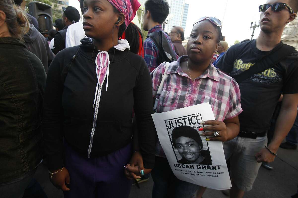 Two ladies hold hold hands a flyer in support of Oscar Grant while protesters gather downtown near city center after jurors convicted Johannes Mehserle on involuntary manslaughter on Thursday July, 8, 2010 in Oakland, Calif.