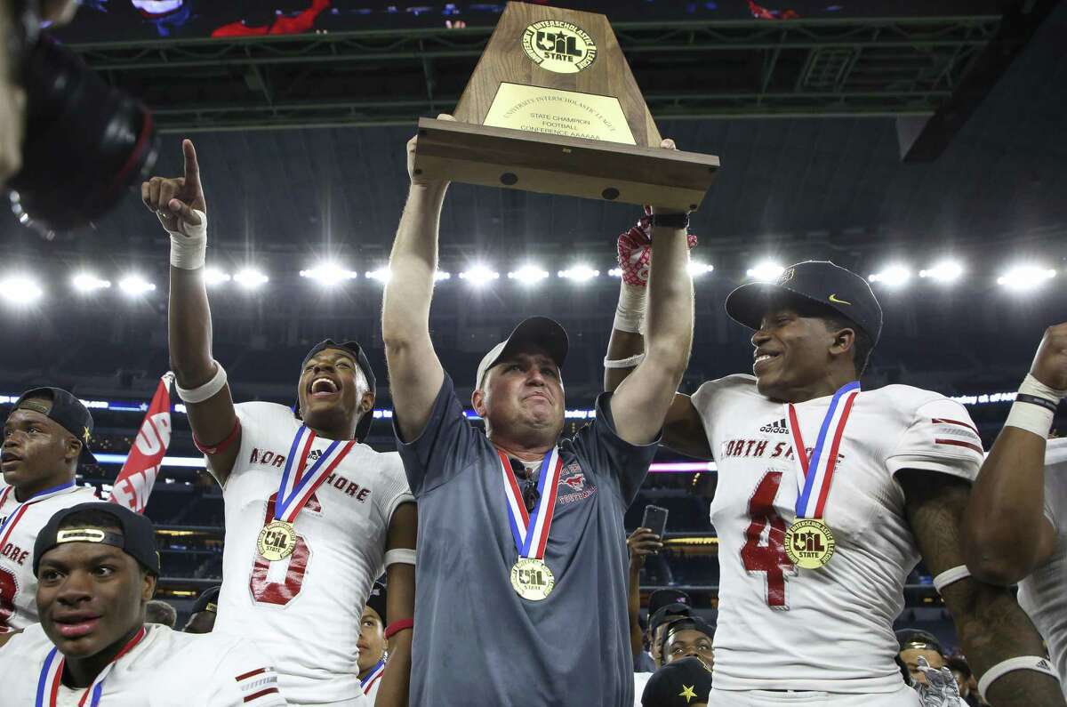 As his players cheer, North Shore coach Jon Kay hoists the state championship trophy and salutes the Mustangs’ fans after Saturday night’s wild 41-36 victory over Duncanville at AT&T Stadium in Arlington.