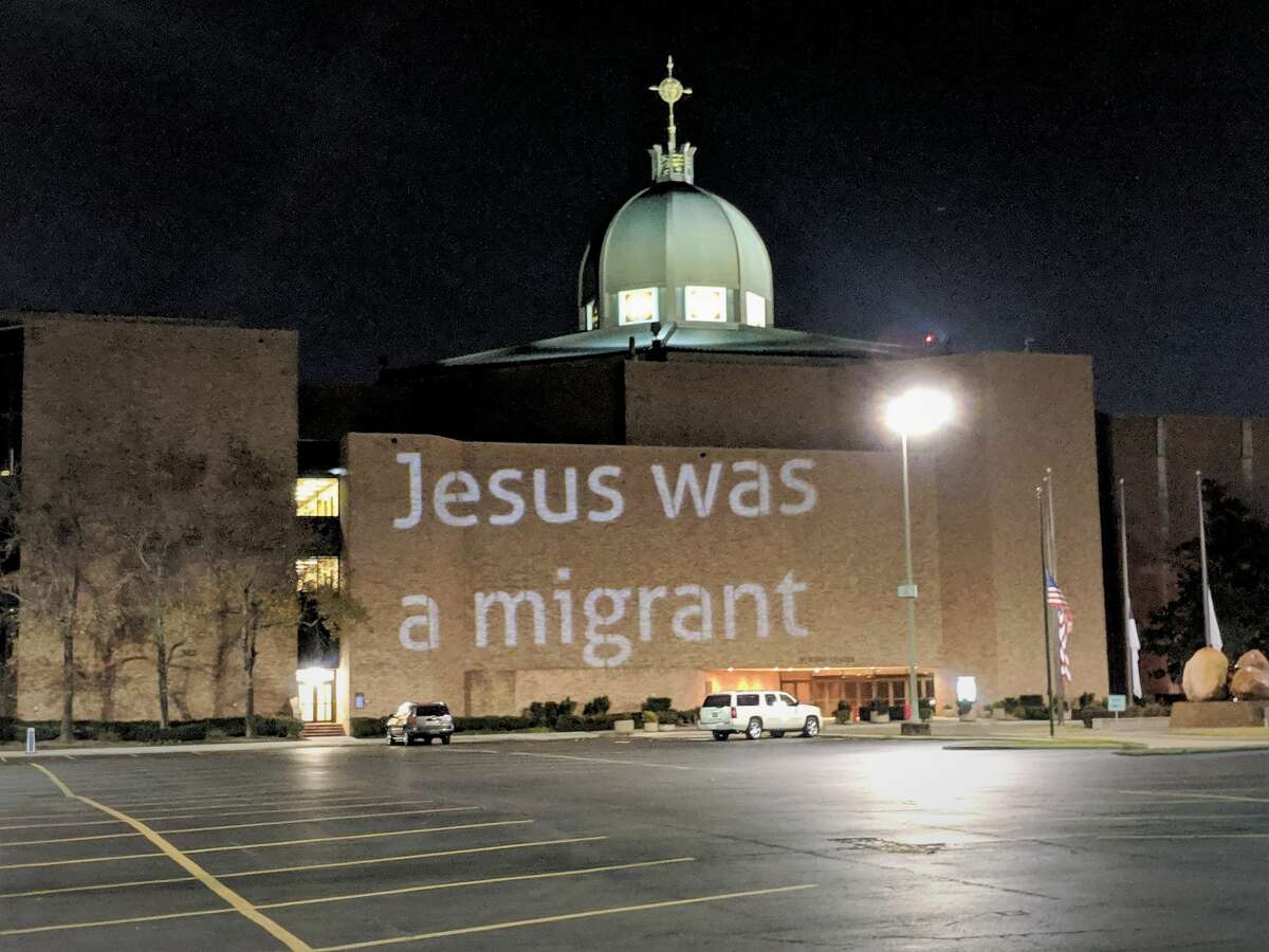 Indivisible Houston projects  the message "Jesus was a migrant" on an exterior wall at Second Baptist Church.