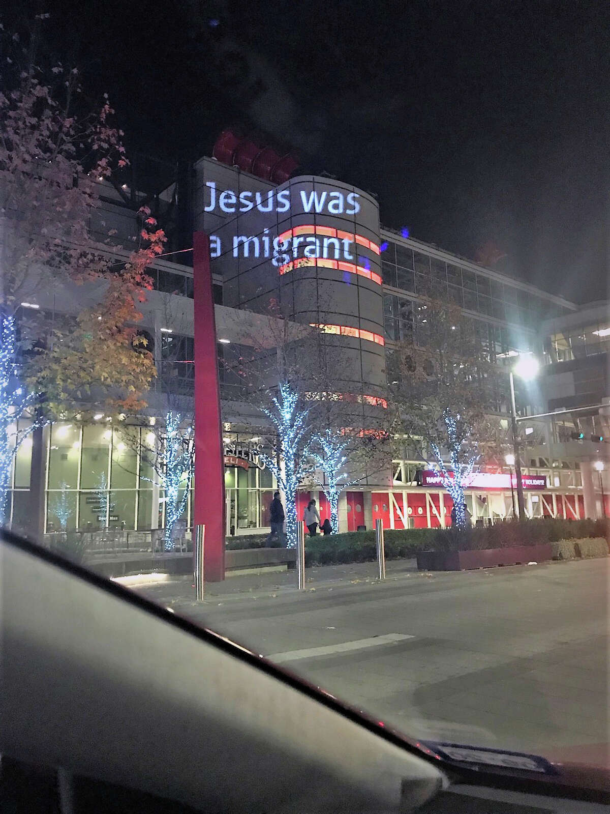 Indivisible Houston projects the message "Jesus was a migrant" on an exterior wall at the George R. Brown Convention Center.