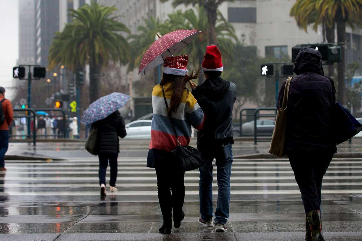 Pedestrians endure the rainy weather on Christmas Eve in San Francisco.