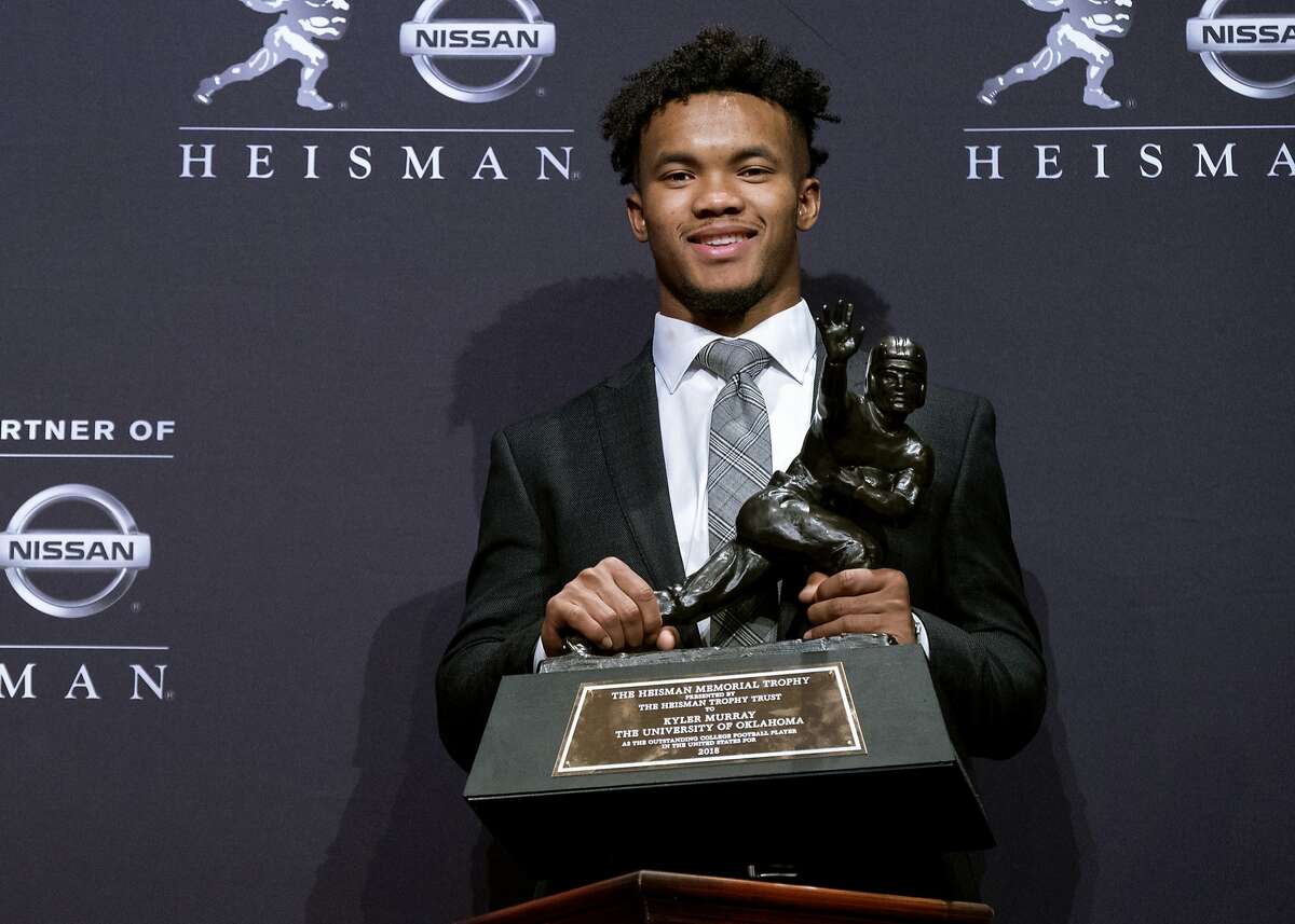 FILE - In this Dec. 8, 2018, file photo, Oklahoma quarterback Kyler Murray holds the Heisman Trophy after winning the award in New York. The latest statistical surge has been led by the quarterbacks who will play in the Orange Bowl semifinal on Jan. 29, when No. 1 Alabama faces No. 4 Oklahoma. Both Heisman Trophy winner Murray (205.72) of Oklahoma and Alabama’s Tua Tagovailoa (202.30) are on pace to break the record for passer efficiency rating set by former Sooners quarterback Baker Mayfield (198.92) last season. (AP Photo/Craig Ruttle, File)