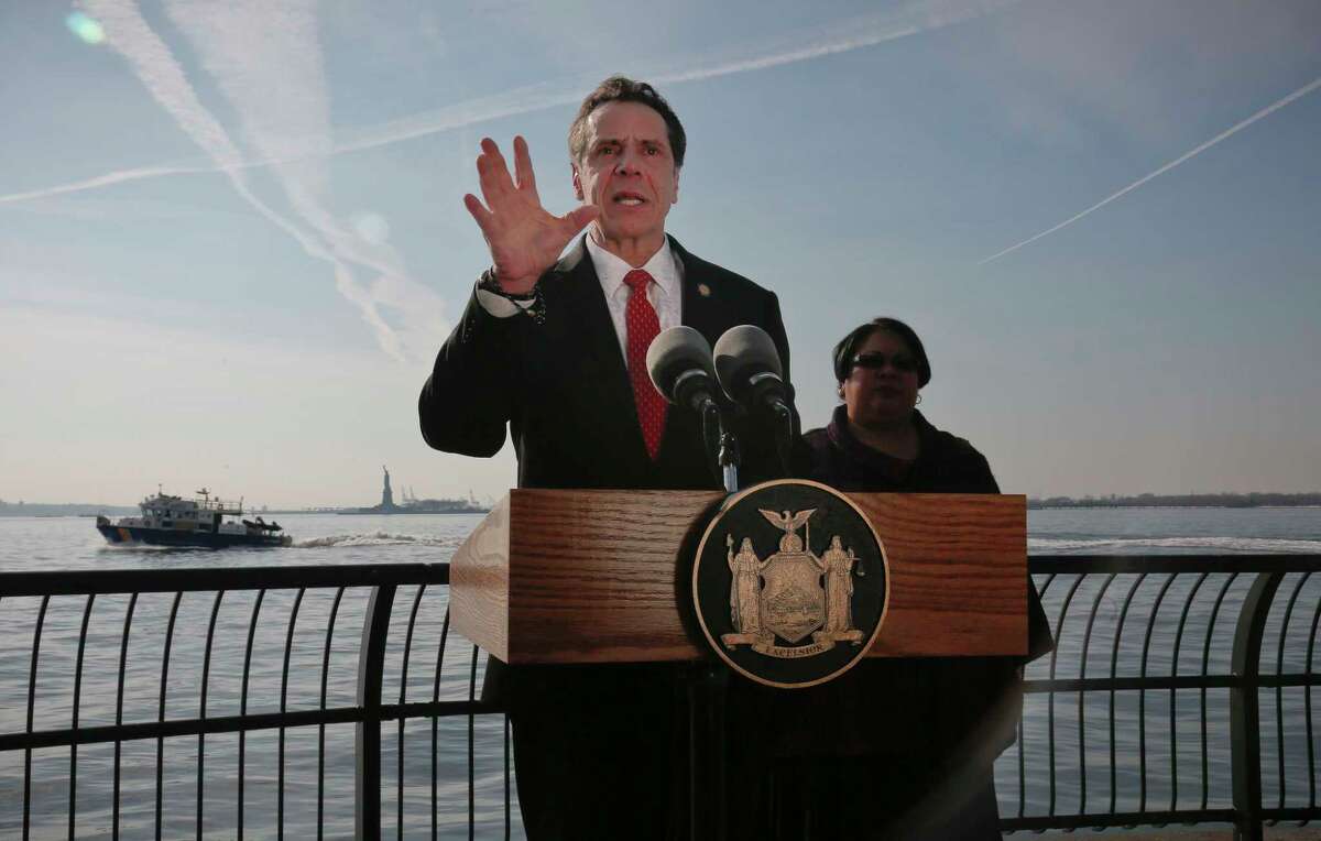 New York Gov. Andrew Cuomo holds a press conference in New York, with the Statue of Liberty and Ellis Island in the distance behind him. (AP Photo/Bebeto Matthews, File)