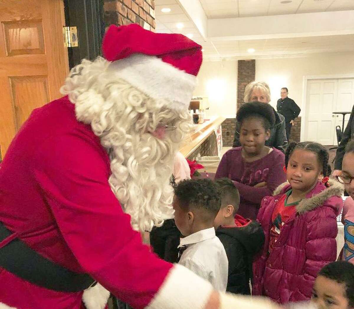 Members of the South Fire District IAFF Local 3918, Connecticut Valley Hospital Police and Middletown Elks Lodge 771 spread joy throughout the city during its annual Adopt-A-Family program Dec. 22. Here, Santa interacts with children.